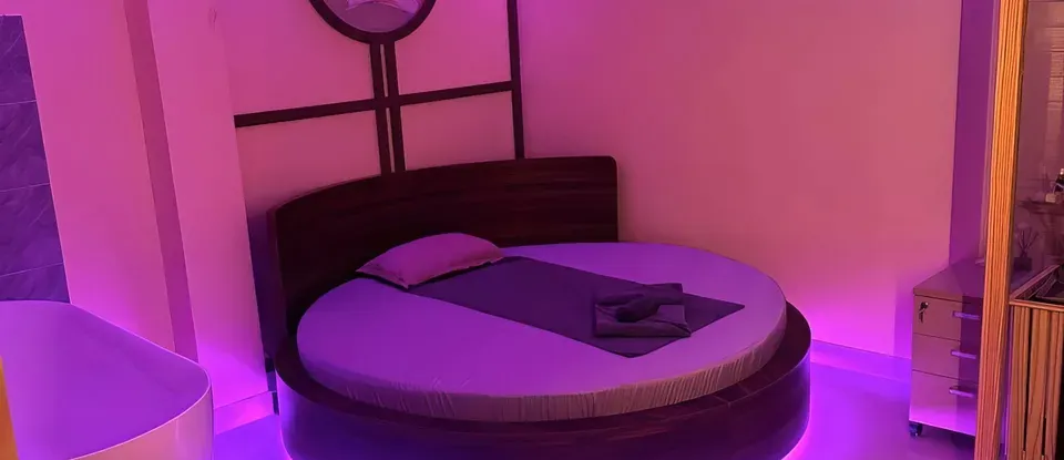 紫色 燈光 亮起的 圓形 床與 浴缸